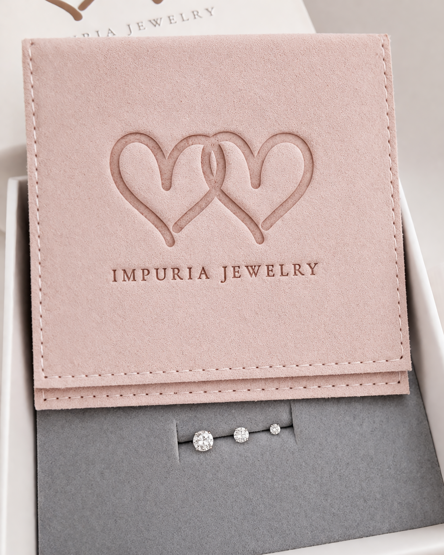 Pink jewelry box with 'Impuria Jewelry' logo containing a flat back stud earrings