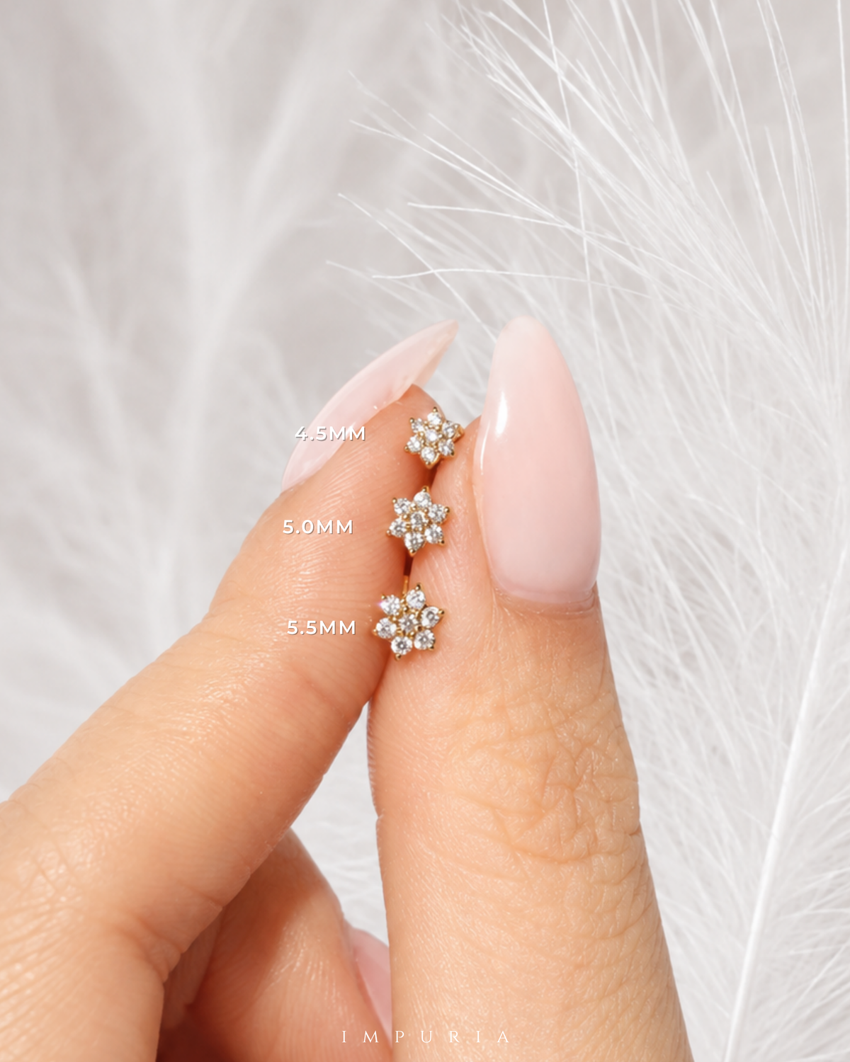 Three small floral stud earrings with clear stones in silver-toned settings are shown on a person's finger, with size labels 4.5MM, 5.